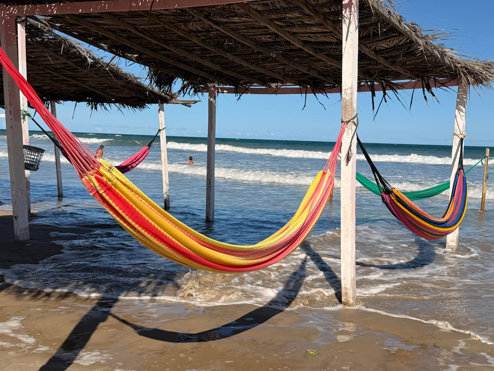 Colorful woven Brazilian hammocks strung up by the ocean shore